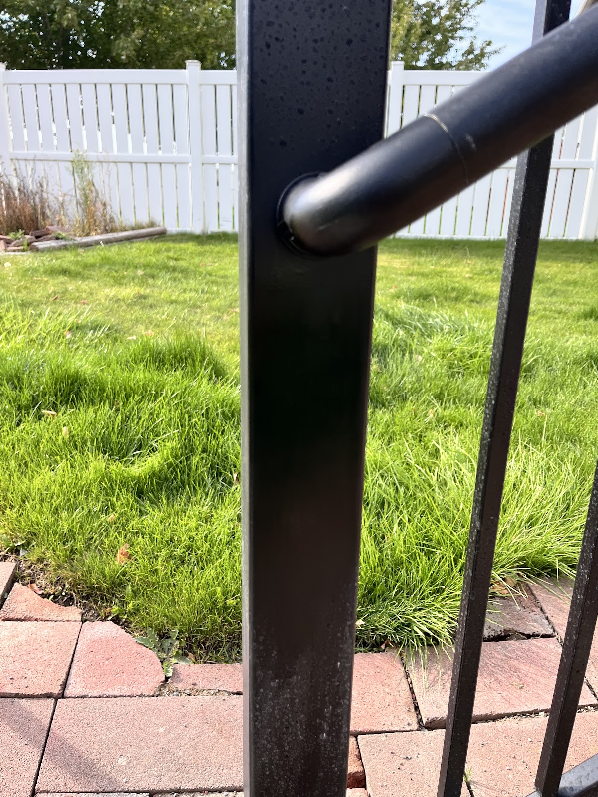 Black metal handrail detail over a paver patio